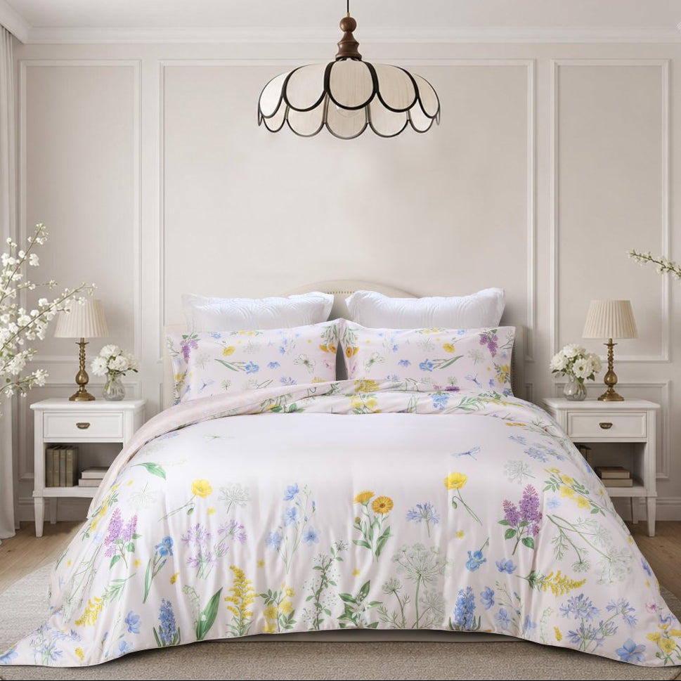 A beautifully styled bedroom featuring a floral print bedding set with a duvet cover and matching pillow shams. The bedding has a delicate pattern of yellow, purple, blue, and green wildflowers on a soft white background.